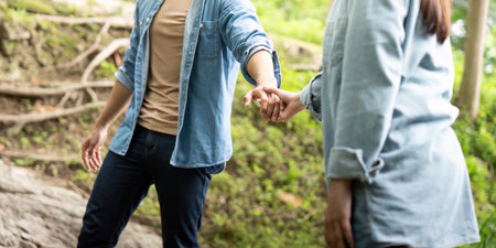 Couple holding hands in nature. Young man and woman sharing a moment of connection by a stream.の写真素材
