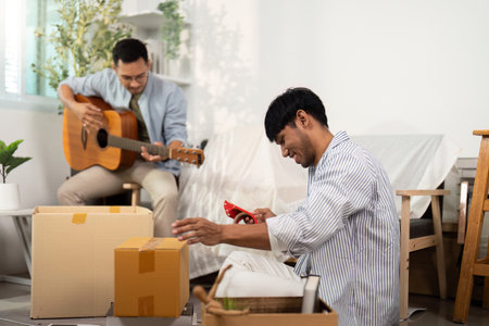 Gay couple enjoying music and unpacking in their new homeの写真素材