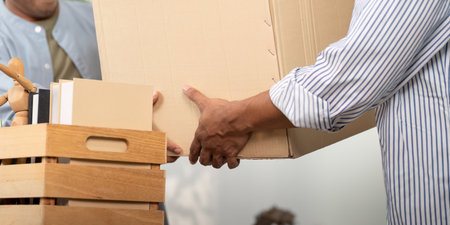 Gay couple sharing a moment while unpacking boxes in their new homeの写真素材