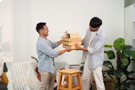 Gay couple exchanging boxes while enjoying their new homeの写真素材