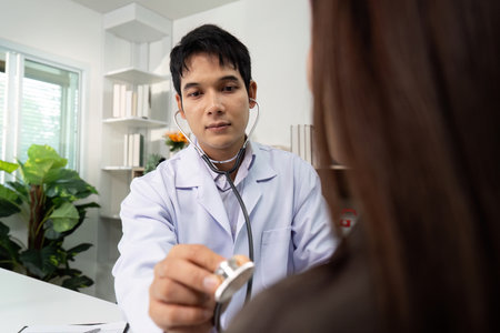 Healthcare Consultation. Doctor using stethoscope on patient in modern clinic.