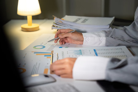Late Night Analysis. A woman reviewing charts and graphs while working late.の写真素材