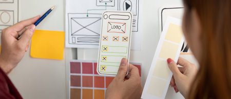 UX and UI Design. Hands holding design mockups and color palettes for mobile app.の写真素材