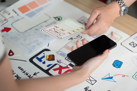 UX and UI Design. Hands interacting with smartphone and design elements for app development.の写真素材
