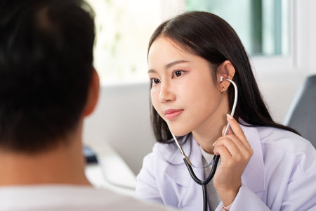 Doctor using stethoscope to examine patient during health check-up in clinic.の写真素材