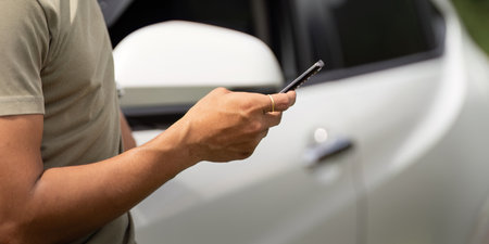 Mobile Connection. Man using smartphone while standing by his car.