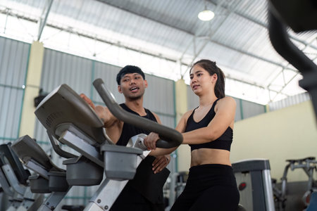 Trainer guiding female athlete on exercise equipment