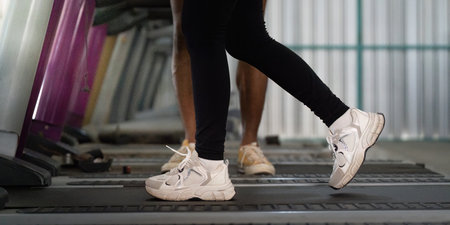 Trainer supporting clients during treadmill exercise sessionの写真素材