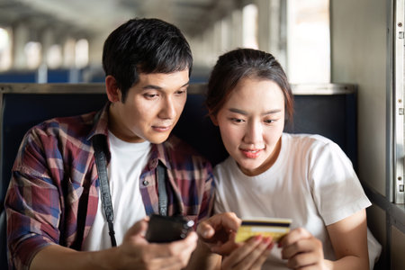 Couple sharing a moment on a train, engaging with technologyの写真素材