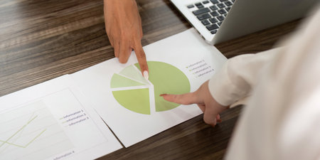 Data Analysis. Two women pointing at a pie chart during a meeting.