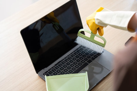 Cleaning Technology. Person using brush to clean laptop screen with care.の写真素材