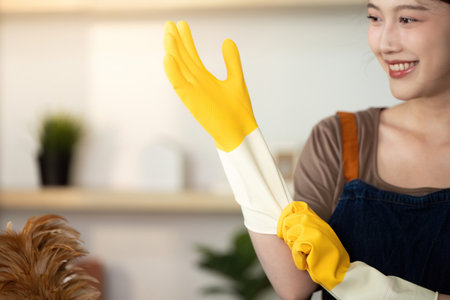 Home Cleaning. Woman smiling while putting on yellow rubber gloves.の写真素材