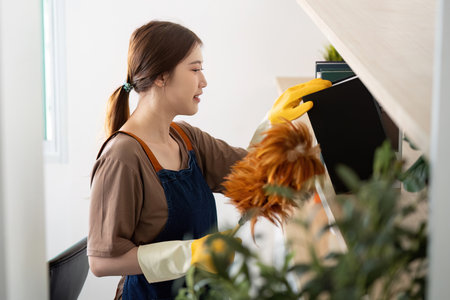 Home Cleaning. Person dusting furniture with a feather duster.の写真素材