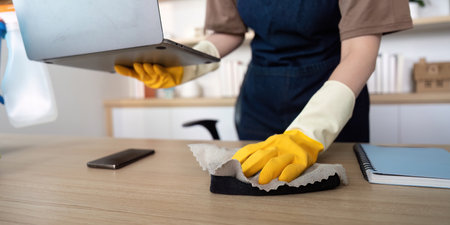 Home Cleaning. Young woman diligently wiping her desk in a stylish home office.