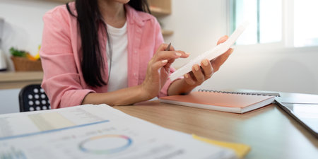 Work from Home Individual using smartphone while analyzing data reports