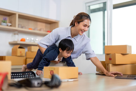 Playful Learning. Mother helping child explore laptop while balancing on packages.の写真素材