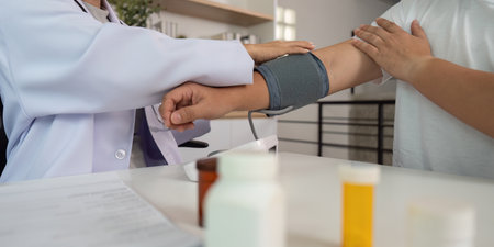 Blood Pressure Assessment. Doctor measuring blood pressure of male patient in clinic.