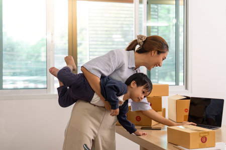 Mother Balancing Work and Parenting with Child on Backの写真素材