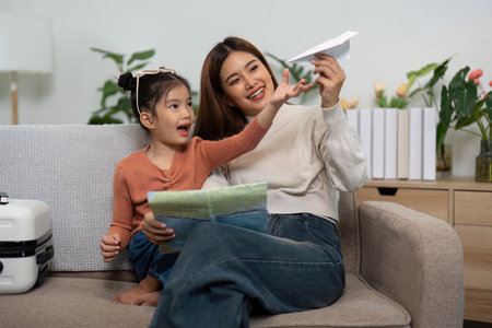 Travel Creativity. Mother and daughter making paper airplanes while preparing for their trip.の写真素材
