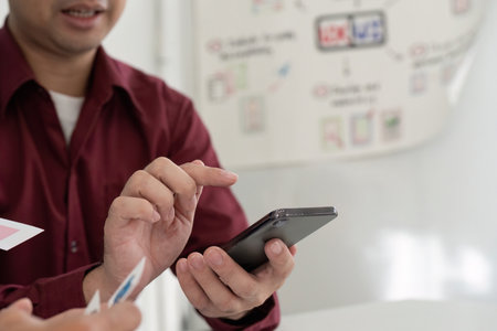 UX and UI Design Collaboration. Team discussing mobile app interface on smartphone.の写真素材