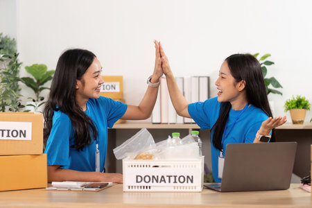 Volunteer teamwork. Two women collaborating on donation project with enthusiasm.