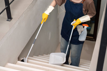 Stair Cleaning. Woman using mop and bucket for thorough home maintenance.の写真素材
