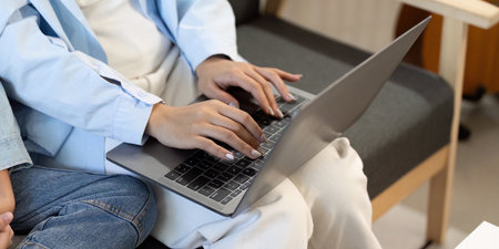 Close-up of hands typing on laptop, showcasing family engagement in learning.