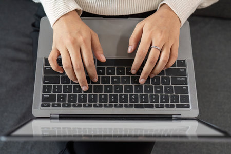 Typing on Laptop. Young woman working on a laptop at home.