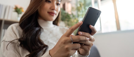 Engaging with Technology. Young woman using smartphone at home.の写真素材