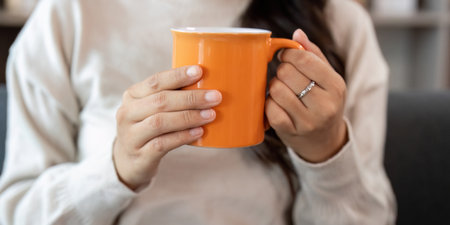 Cozy Moment. Woman holding orange mug, enjoying warm beverage at home.