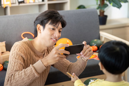 Capturing Memories. Father taking photos of son during Halloween crafting.