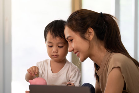 A mother teaching her child about saving money with a piggy bank.の写真素材