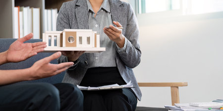 Real Estate Agent Holding Model Home During Client Meeting