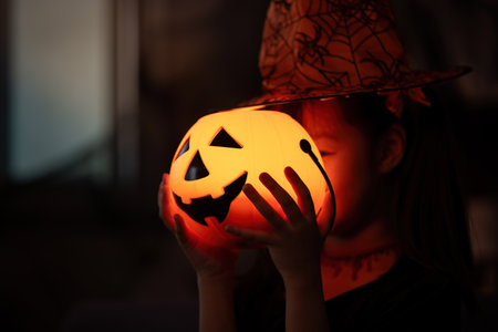 Halloween Fun. Child with a glowing pumpkin lantern, celebrating the spooky season.の写真素材