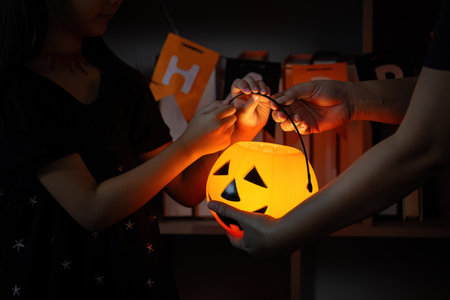 Halloween activity. Sharing a glowing pumpkin lantern between a child and adult.の写真素材