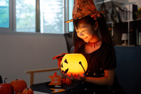 Halloween Celebration. Young girl holding glowing pumpkin lantern with joy.の写真素材