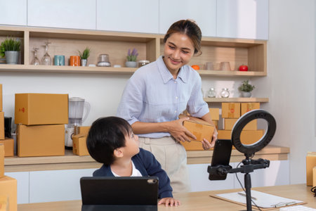 Entrepreneurial Spirit. A mother smiling while managing her online business with her child.の写真素材