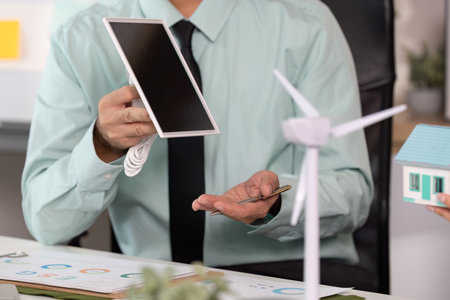 Innovative Sustainability. Professionals discussing renewable energy solutions and eco-friendly building designs.の写真素材