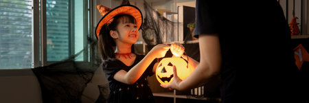 Halloween Joy: Girl Presenting Pumpkin Lantern to Parentの写真素材