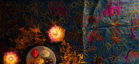Diwali Festivity. Traditional sweets and glowing candles on a colorful table.