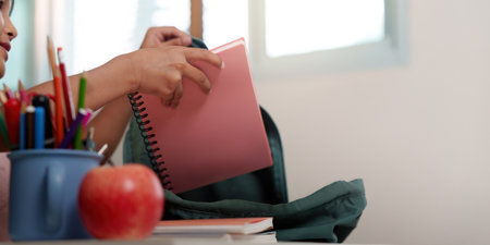Back to School. Young girl unpacking notebook from backpack.の写真素材