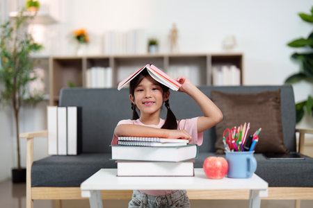 Back to School. Happy child posing with books while studying at home.の写真素材