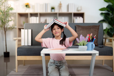 Back to School. Child playfully balancing books on head while studying.の写真素材