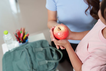 Child receiving healthy apple from parent before schoolの写真素材