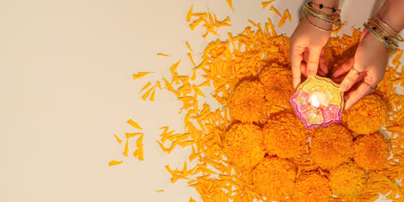 Diwali Ritual. Hands placing a decorative lamp amidst marigold flowers for celebration.の写真素材