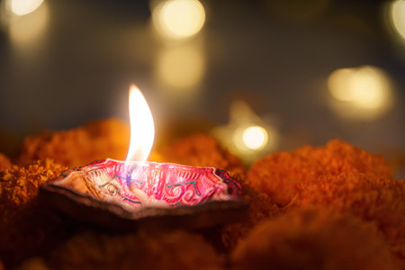 Diwali Celebration. A diya lamp shining brightly surrounded by marigold petals.