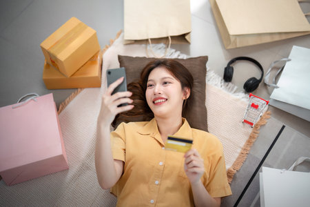 Online shopping. Smiling woman enjoying her shopping experience with a credit card.の写真素材