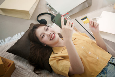 Online shopping. Young woman relaxing while shopping online with a credit card.の写真素材