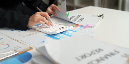 Financial Review. Professional analyzing financial documents and calculating with a calculator.