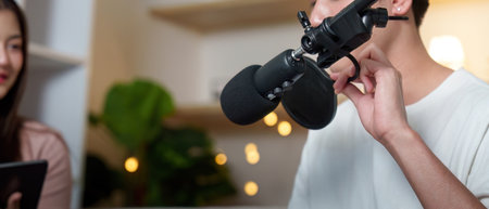 Podcasting focus. Close-up of a young man adjusting a microphone during a recording.の写真素材